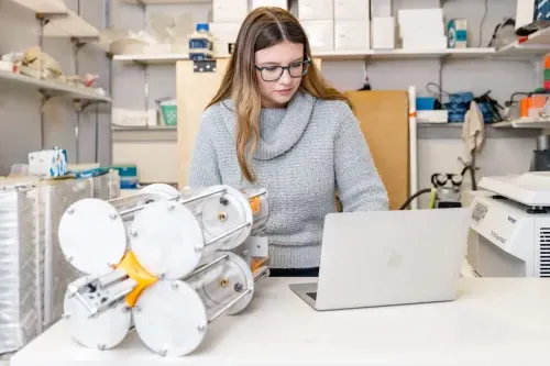 A marine science student works on their laptop in a lab