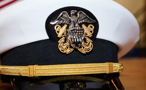 A military captain's hat with American flags in the background