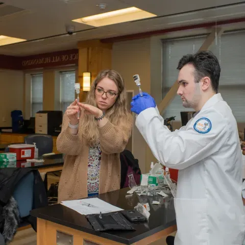 UNE pharmacy students draw vaccines from vials in a lab setting